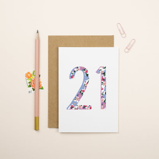 A greeting card with the number 21 on the card. The pattern is floral and it is in blue and purple